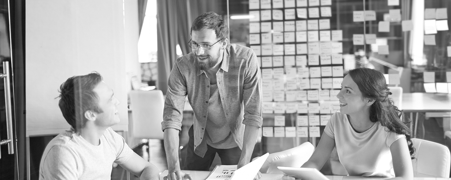 Image of three adults talking around a conference table.